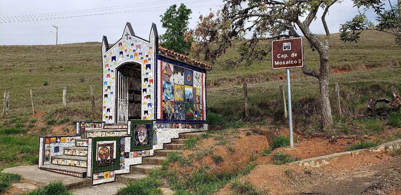 A capelinha de mosaico do Paiol vista da estrada, ao lado da placa 'Cap. de Mosaico II'