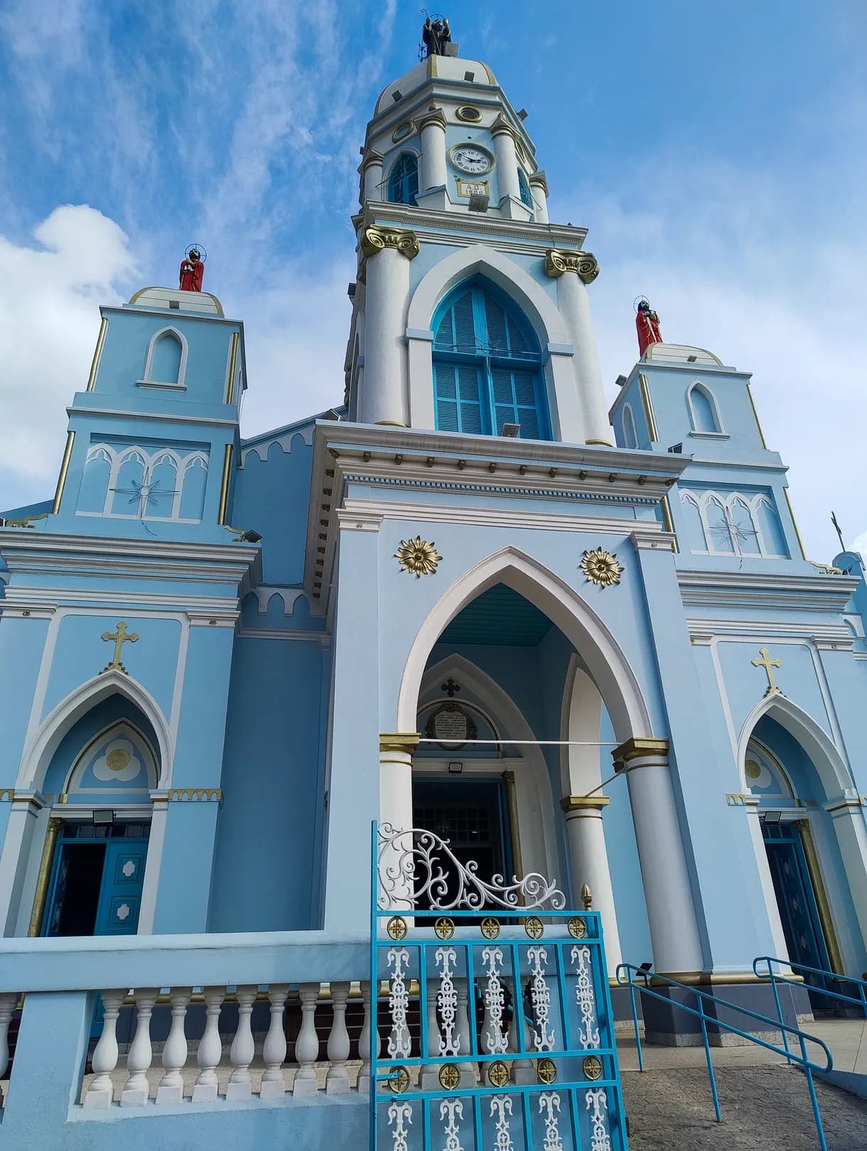 Fachada da Igreja Matriz de São Bento do Sapucaí vista de frente, com as duas torres, o gradil branco e a escadaria de acesso