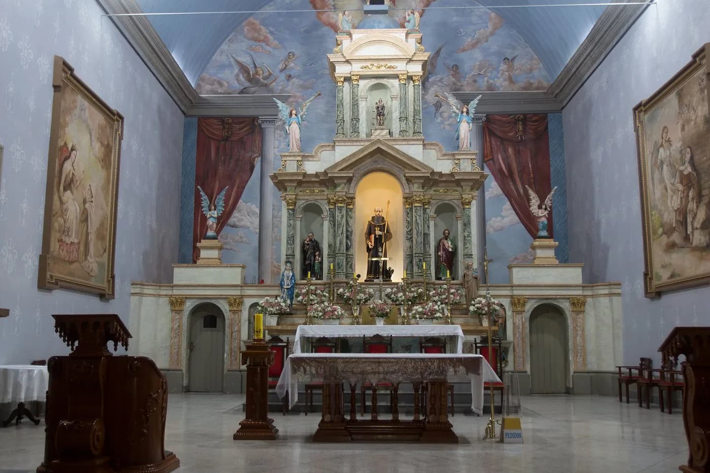 Frontão e torre do relógio da Igreja Matriz de São Bento do Sapucaí vistos de baixo, contra o céu de fim de tarde