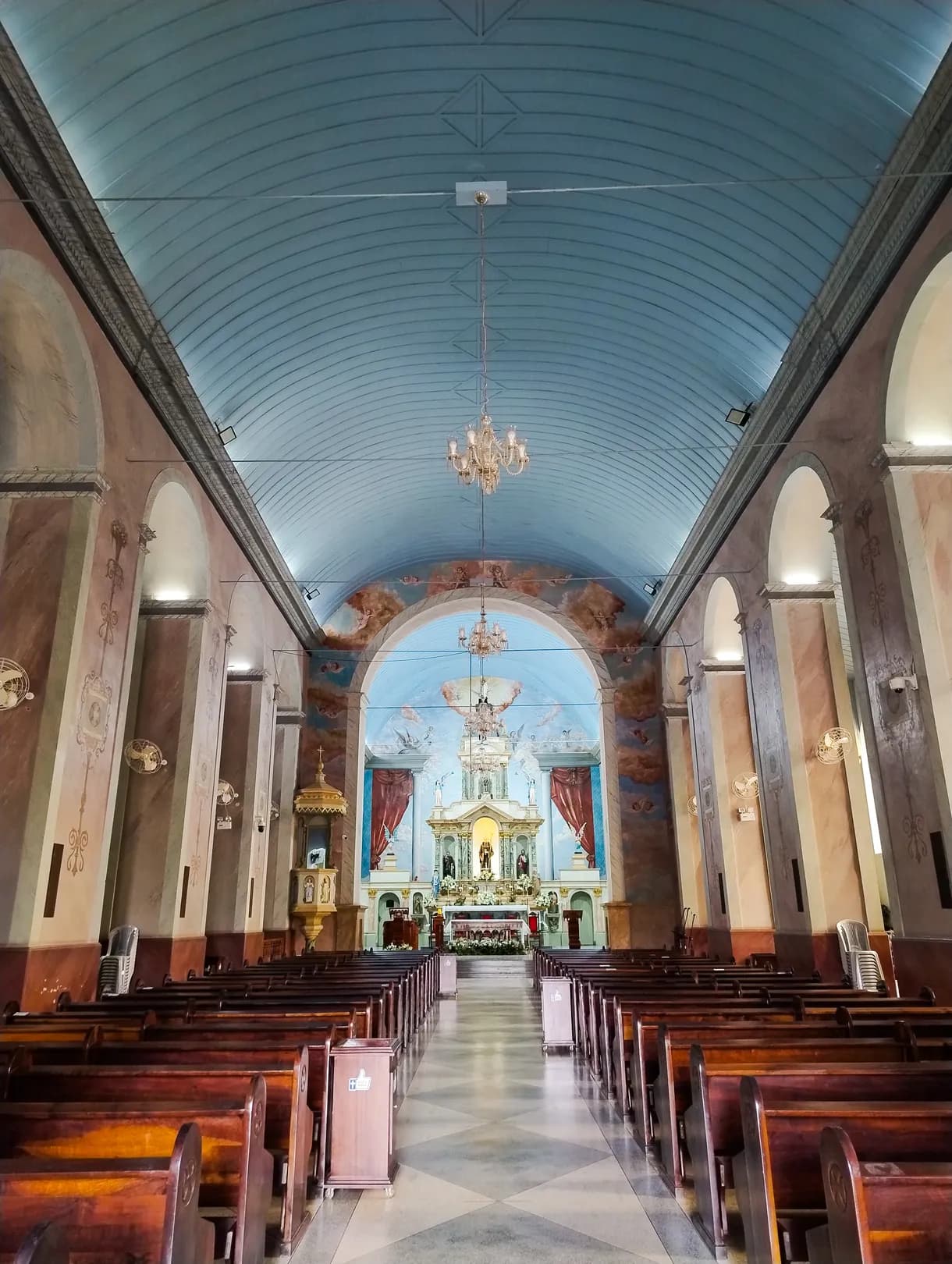 Altar-mor da Matriz em dourado e branco, entre pinturas murais de cortinado vermelho