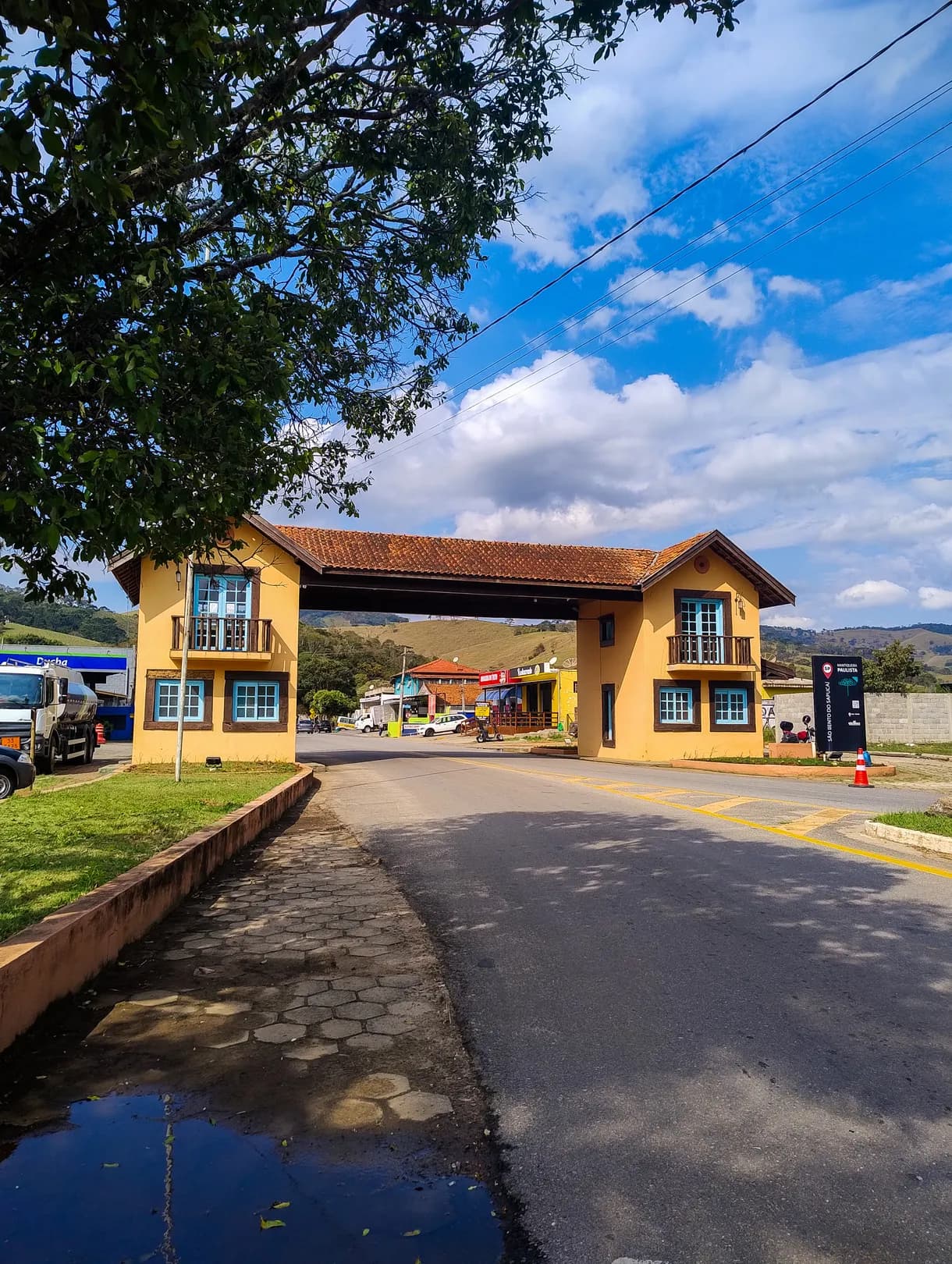 Portal da Cidade cobrindo a pista na chegada pela rodovia, com telhado de telha, janelas azuis e o Centro de Informação ao Turista