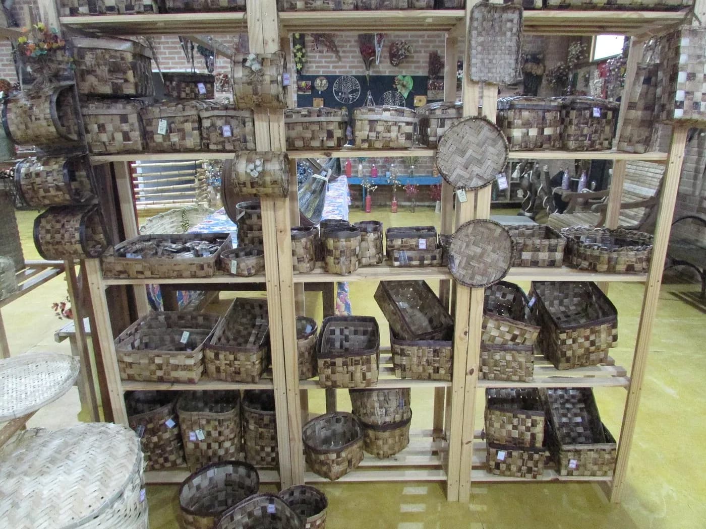 Estantes de madeira com cestos, bandejas e peneiras de palha trançada à venda na loja