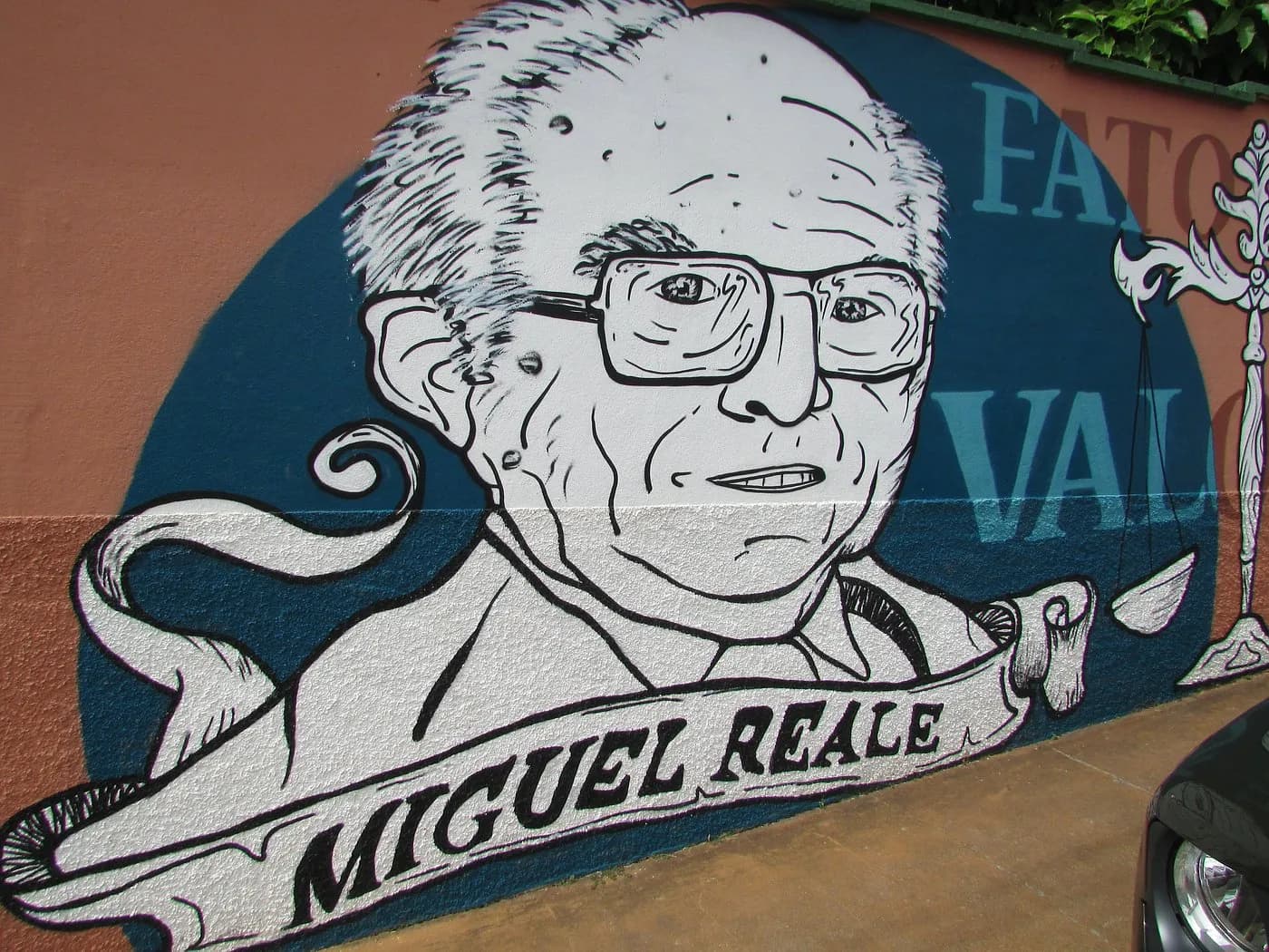 Mural com o retrato de Miguel Reale em traço preto sobre fundo azul, na parede da rua