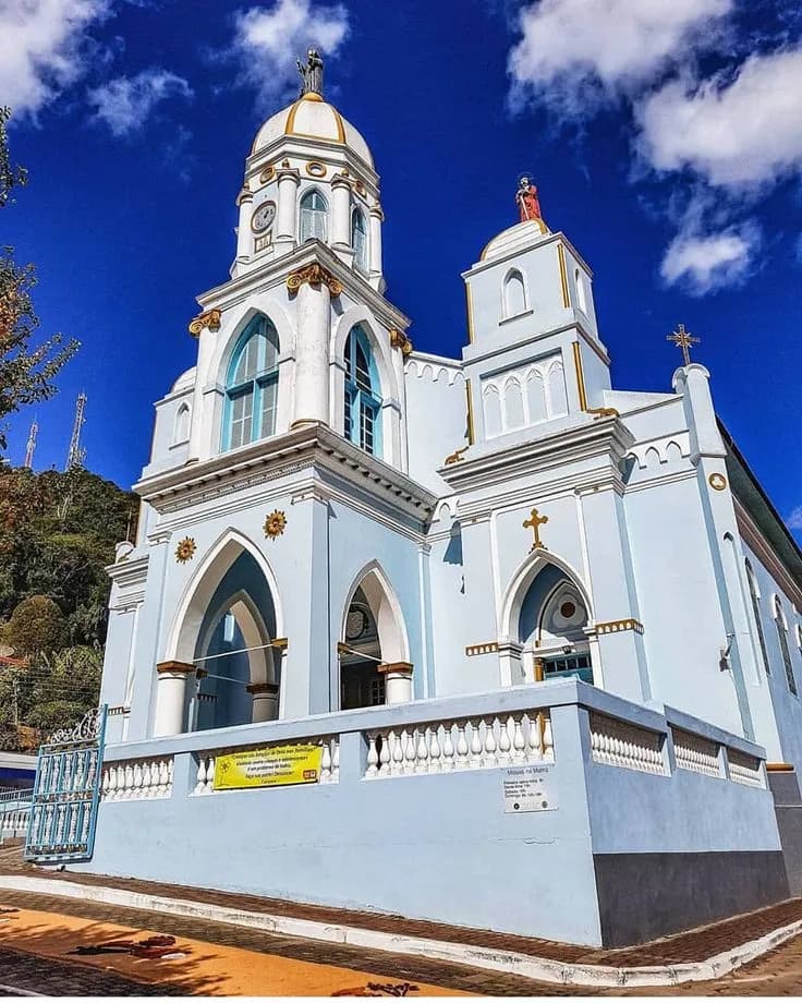 Fachada azul-clara e branca da Igreja Matriz de São Bento, em São Bento do Sapucaí, com a torre do relógio, arcos góticos e balaustrada